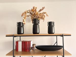 a shelf with three black vases and a bowl at Sun and Golf Holidays at Mar Menor Golf Resort in Torre-Pacheco