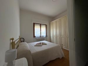 a white bedroom with a bed and a window at Appartamento Magnolia in Mercatale Val Di Pesa