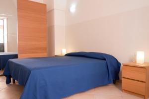 een slaapkamer met een blauw bed en een houten kast bij Casa Caporosso Giusti in Maruggio