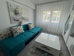 a living room with a blue couch and a table at Apartament Silver Nest Comanesti in Comăneşti
