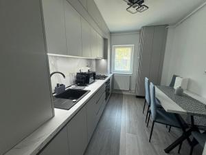 a kitchen with a sink and a table with chairs at Apartament Silver Nest Comanesti in Comăneşti