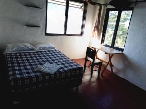 a bedroom with a bed and a desk and two windows at Cuarto 2 in San Marcos La Laguna +6 photos