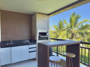 a kitchen with a counter and a balcony with palm trees at Mandara Lanai Resort - Porto das Dunas in Aquiraz