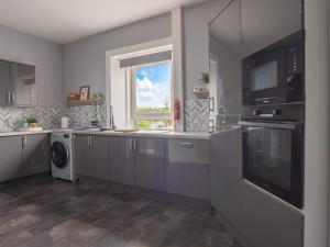 a kitchen with stainless steel appliances and a window at Pitchside Escape in Ayr +23 photos