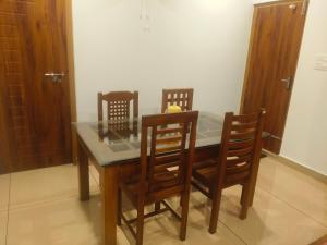a dining room table with four chairs and a glass top at Wayanad Home stay in Kaniyāmbetta +6 photos