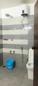a bathroom with a toilet and a blue bucket at Wayanad Home stay in Kaniyāmbetta