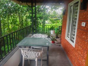 a balcony with a table and two chairs on it at Wayanad Home stay in Kaniyāmbetta