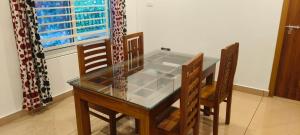 a glass table and two chairs in a room at Wayanad Home stay in Kaniyāmbetta