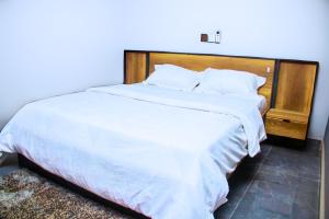 Un dormitorio con una gran cama blanca con cabecero de madera. en Chanan Court Apartment, en Accra