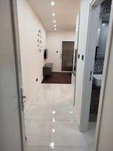 a bathroom with a white tile floor and a hallway at Apartman Ani in Vinkovci