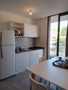 Il comprend une cuisine équipée d'un réfrigérateur blanc et d'une table avec des chaises. dans l'établissement Sam Lake 3, à Villa Carlos Paz
