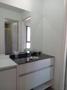 une salle de bains blanche avec un lavabo et un miroir dans l'établissement Sam Lake 3, à Villa Carlos Paz