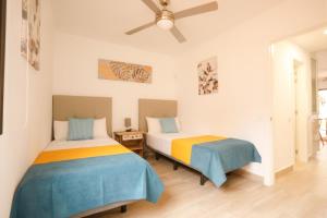 two beds in a room with a ceiling fan at Oasis Dunas Corralejo in Corralejo +51 photos