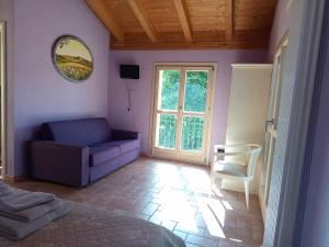 una camera da letto con un divano viola e una sedia di Agriturismo La Palazzina di Gorgognano a Pianoro