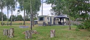 a mobile home with an umbrella in a field at Domek holenderdki ZaCisze 2 in Augustów