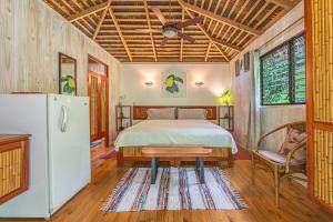 a bedroom with a bed and a table and a refrigerator at Chalet Jardin Tropical in Ojochal