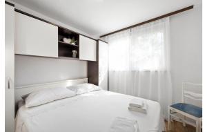a bedroom with a white bed and a window at 2 Bedroom Nice Home In Brodarica in Brodarica