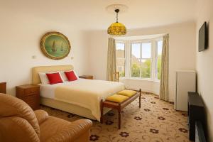 a bedroom with a bed and a chair and a window at The Queens Road Hotel in Isle of Wight