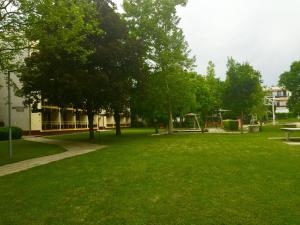 Kosztolányi Apartmanház في بالاتونفوريد: حديقة بها ملعب وطاولة نزهة وأشجار