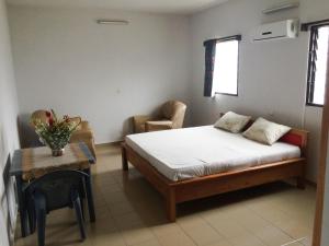 a bedroom with a bed and a table and a chair at Appartements Lome Marie Antoinette in Atigan