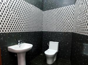 a black and white bathroom with a sink and a toilet at Apeksha Sunset in Addalachenai