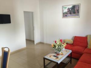 a living room with a red couch and a table with flowers at Appartements Lome Marie Antoinette in Atigan