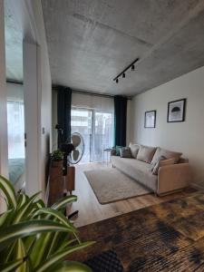a living room with a couch and a large window at VizzitUs Premium Apartament Łódź Manufaktura in Łódź