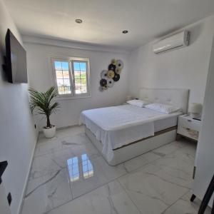 a white bedroom with a bed and a potted plant at Azure Bliss in Costa de Adeje