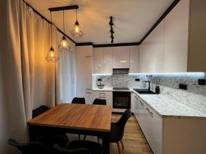 a kitchen with a wooden table and a dining room at Warmia Dream Apartament in Olsztyn