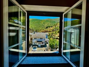 a window with a view of a house with a yard at Égua Nature House in Piódão