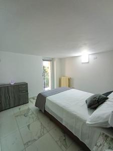 a white bedroom with a large bed and a window at La Fontana in Montalbano