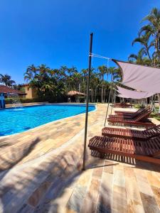 a group of lounge chairs next to a swimming pool at Flat na Praia de Maresias - 100 metros da praia in São Sebastião