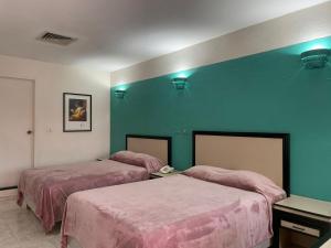a room with two beds and a green wall at Hotel Tamazunchale in Tamazunchale