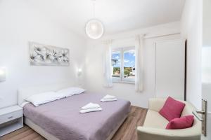 una camera da letto bianca con un letto e una sedia di Apartment Baras a Nin