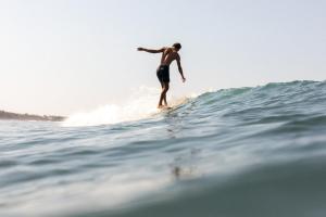 a man riding a wave on a surfboard in the ocean at Samas Hotel - La Saladita in Temalhuacán