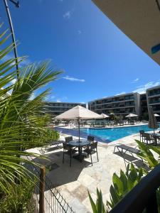 a patio with a table with an umbrella and a pool at Muro Alto Comfort - Family Flat - 2 quartos in Ipojuca