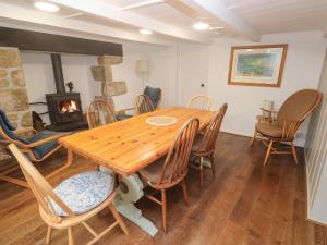 a dining room with a wooden table and chairs and a fireplace at Sunnyvale Cottage in Penzance