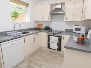 a kitchen with white cabinets and a sink at Sunnyvale Cottage in Penzance +28 photos
