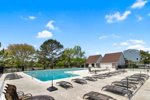 a swimming pool with chaise lounge chairs next to a resort at Spring lake 601 in Rehoboth Beach
