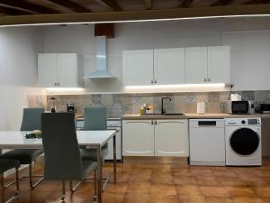 a kitchen with white cabinets and a table and chairs at Santinho house 2 in Beja