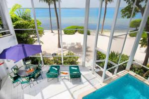 a view from the balcony of a resort with a pool and the beach at Lluxurious villa Rum Point, North Side, Islas Caimán 