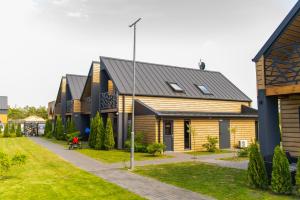 a house with a black roof and a yard at Domki Sarbinowo Elizjum in Sarbinowo