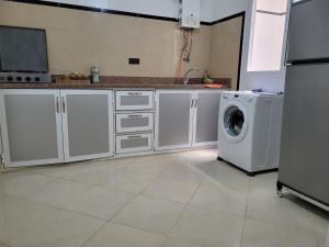 a kitchen with white cabinets and a washing machine at Superbe Appartement bouki in Al Hoceïma +10 photos