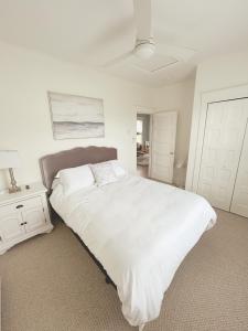 a white bedroom with a large bed and a night stand at Magnolia Moon Cottage at East Lake Shores in Cherry Valley +27 photos