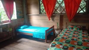 a bedroom with two beds in a room with windows at hospedaje Casa Jaguar in Macedonia