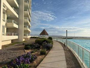 a walkway next to a building next to the water at Acogedor Apartamento en Laguna del Mar in La Serena