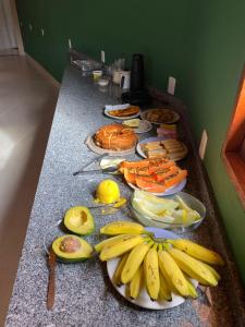 a counter topped with plates of bananas and other foods at Recanto Arco Íris in Palmeiras +35 photos