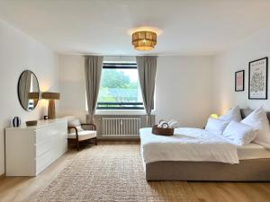 a white bedroom with a bed and a mirror at HyggeLiving - DELUXE - 90qm - Balkon - Gartenblick - 55 Zoll TV - Boxspringbetten - Hunde - Kinder - Fahrradkeller in Bad Harzburg