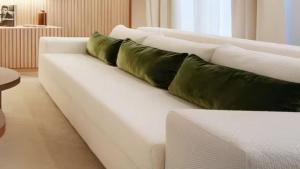 a white couch with four green pillows on it at Ski Chalet Stubenbach Lech in Oberlech