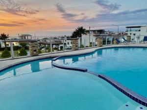 a large blue swimming pool with a sunset in the background at Beach House 8 Tijuana in Tijuana